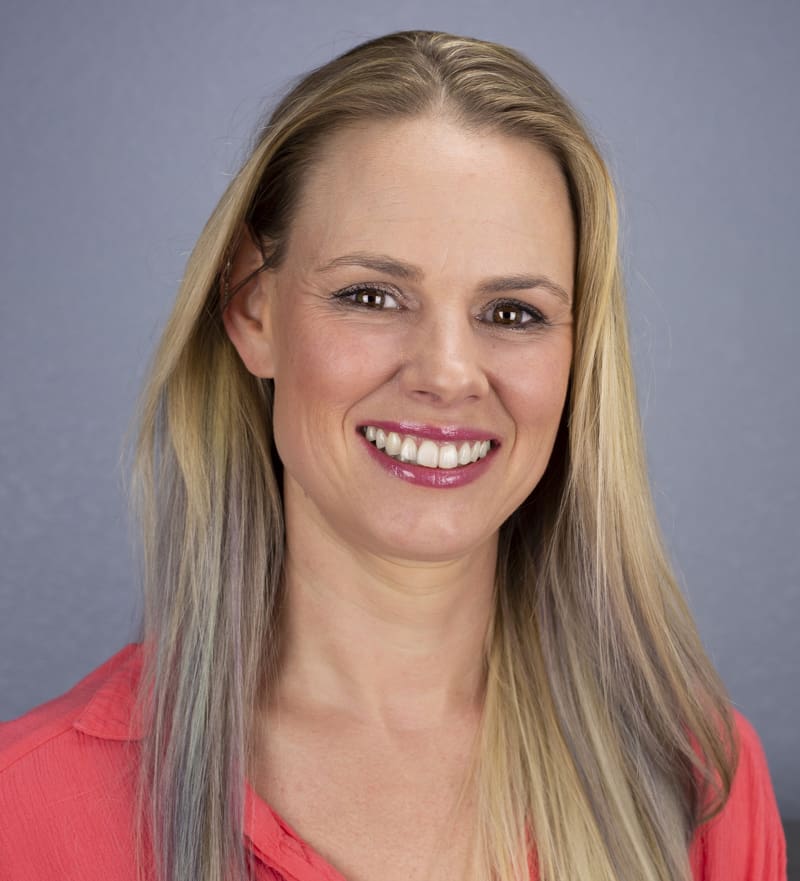 A woman with long blonde hair smiles for the camera.